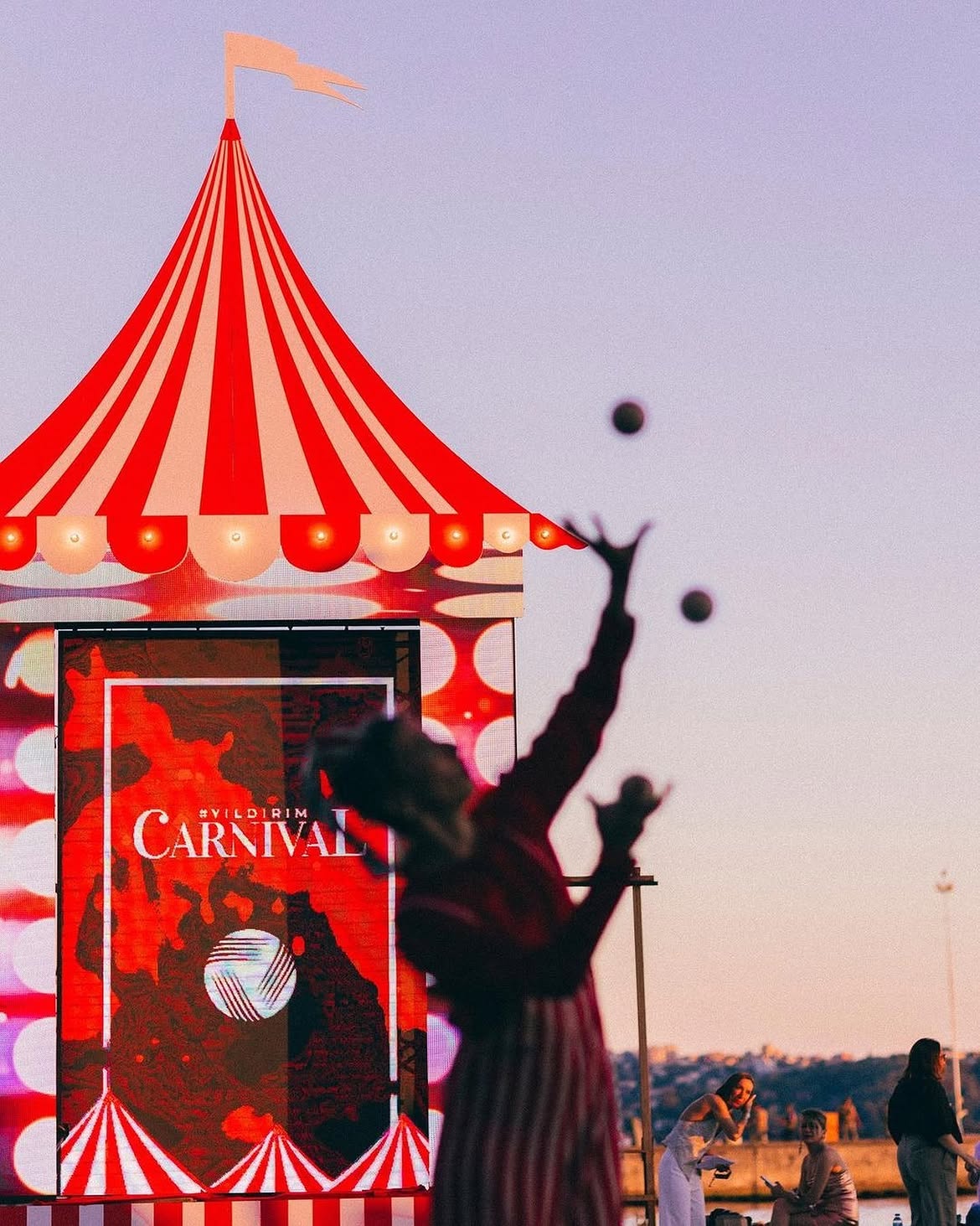 Red and white carnival tent performer at a waterfront celebration